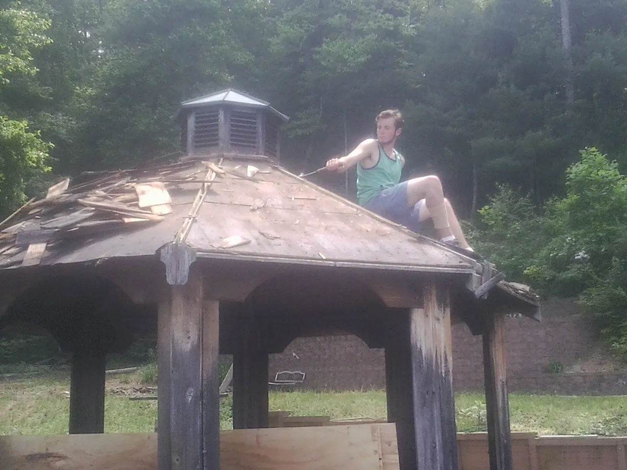 Tearing the old roof off a wooden gazebo before new shakes in Dixie