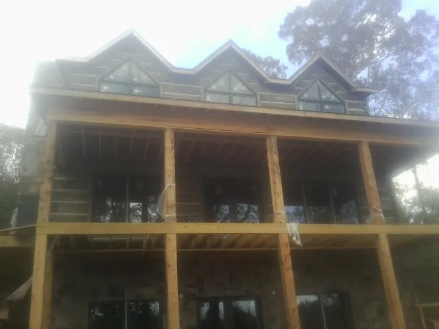 Dormers and porch framing on a large log home under construction — Roof Coating work by our crew in Dixie