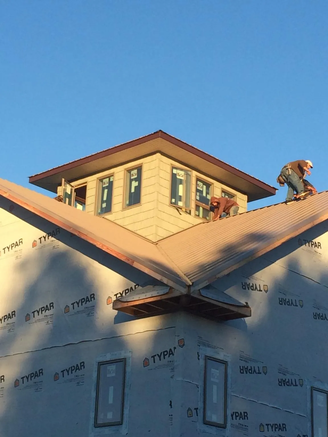 Roofers working around a rooftop cupola on a new metal roof at sunset — Roof Waterproofing in Dixie by Roofing Brothers